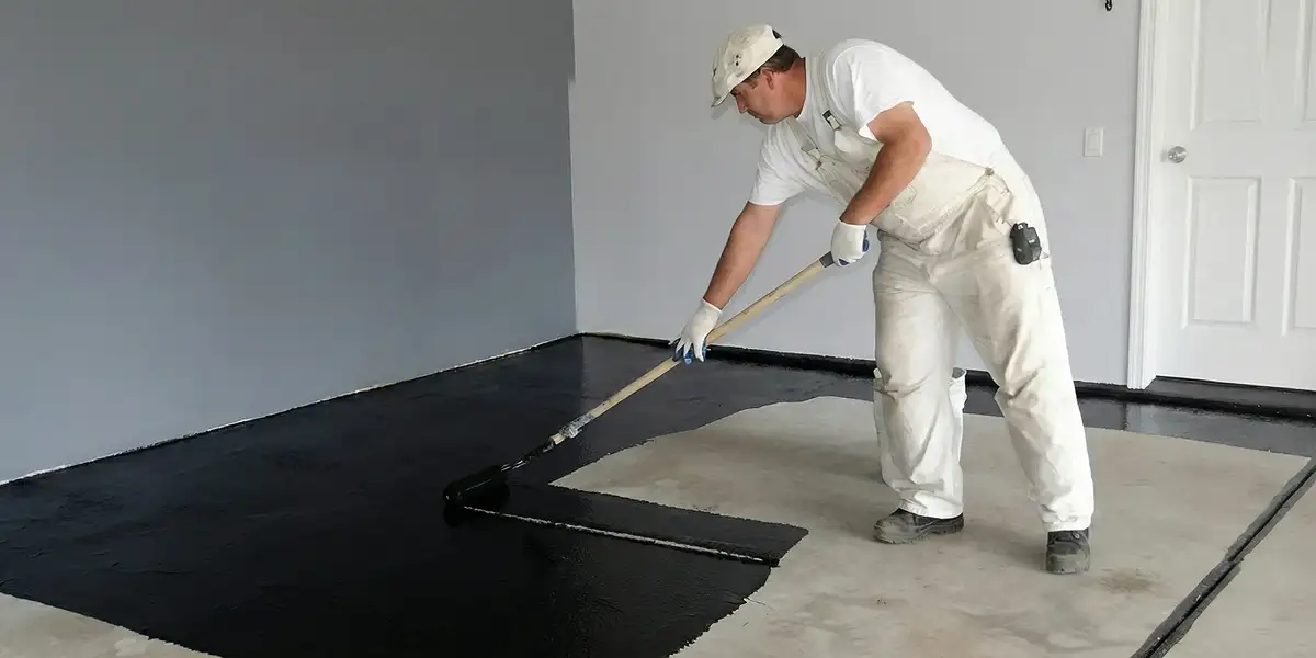 basement waterproofing professional applying waterproof coating to protect a basement floor in Minneapolis, MN